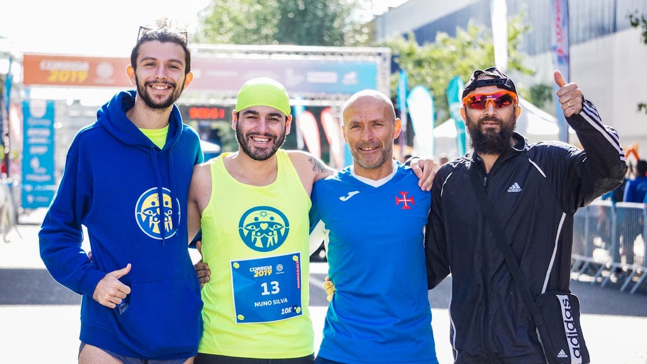 services-01 Four male marathon runners celebrating after a race, smiling and posing for the camera outdoors.