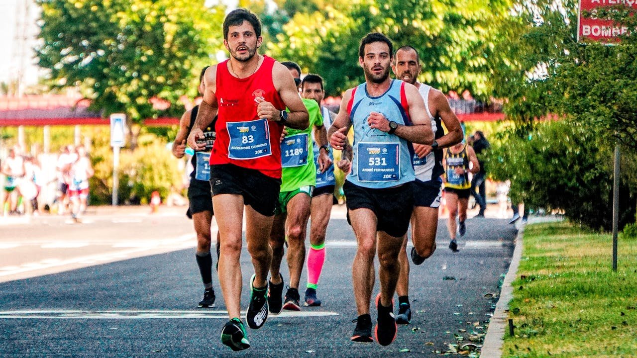 heros-img Group of male runners participating in an outdoor marathon on a sunny day, displaying athletic endurance.
